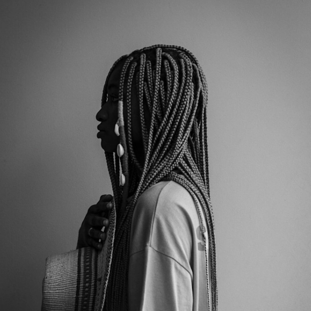 Portrait with traditional braids and a woven bag